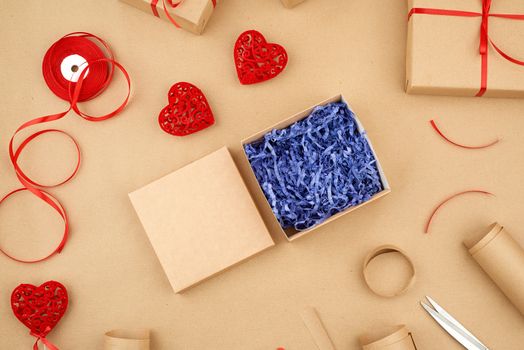 brown kraft paper, packed gift boxes and tied with a red ribbon, red heart, set of items for making gifts. Package design, top view 