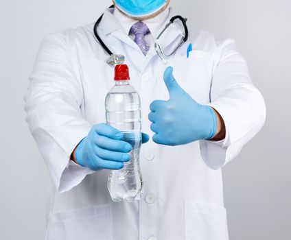 doctor in a white coat and blue latex gloves holds a transparent bottle of water, you need to consume more water to feel better