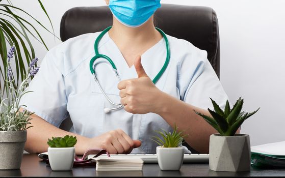 medic woman in white coat showing like gesture in hand, approval concept, doctor's workplace