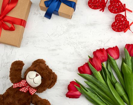 cute brown teddy bear, bouquet of red tulips, gift box, festive backdrop for birthday, Valentine's day, anniversary, top view