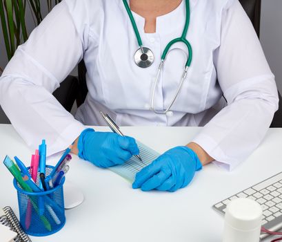 young woman doctor in a white coat, sterile medical gloves writes a prescription on a form, therapist sits on a chair at a white table, workplace