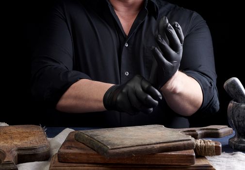 chef in black uniform wears black latex gloves before cooking, low key