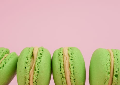 green round baked macaroon macarons on a pink background, delicious popular french dessert, copy space