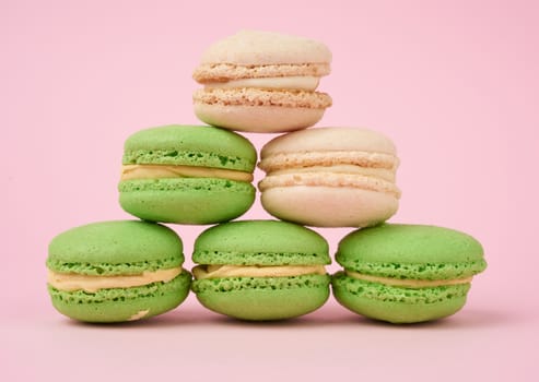 stack of white and green round almond flour cakes macarons with cream on a pink background, delicious cake