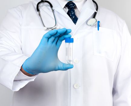 doctor in a white coat and blue sterile latex gloves holds a plastic jar for stool analysis, white background