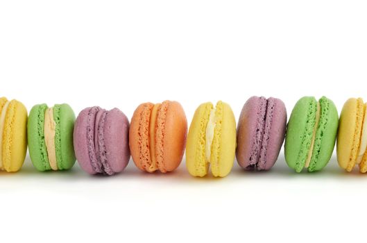 multicolored round baked macaroon cakes isolated on a white background, dessert stands in a row