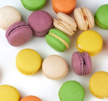 round baked multi-colored almond flour cakes macarons, dessert  on a white background, top view