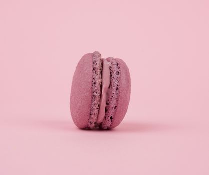 one round purple dessert of almond flour with cream macaron on a pink background, delicious cake