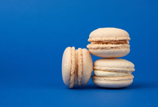 stack of white round baked almond flour cakes macarons on a dark blue background, delicious popular french dessert, copy space