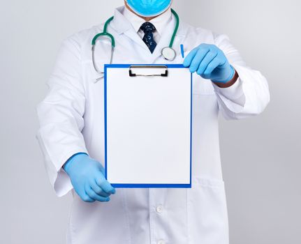 male doctor in a white coat, blue latex gloves, a stethoscope hanging on his neck holding a paper holder with a white blank sheet, place for writing a prescription and text