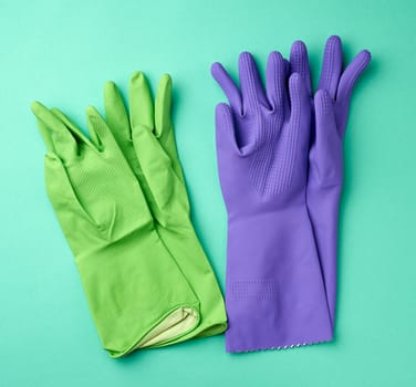 rubber green and purple cleaning gloves on a green background, flat lay