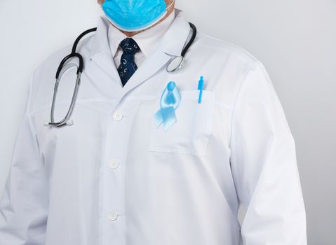 male doctor in a white coat and tie stands. On the pocket pinned a blue ribbon in the shape of a loop, symbol of the fight and treatment of prostate cancer