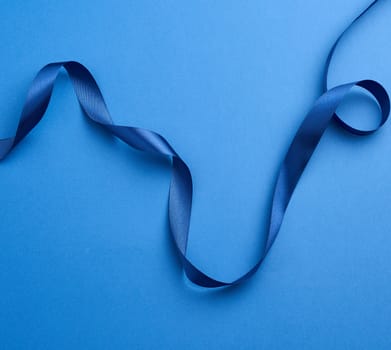 blue silk thin ribbon twisted on a blue background, trendy classic color, close up