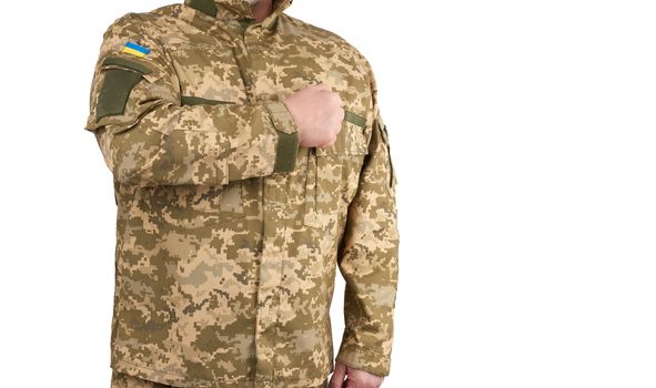 Ukrainian man warrior dressed in a military pixel uniform stands on a white background, soldier put a hand to his chest as a sign of respect, honor of the state symbol