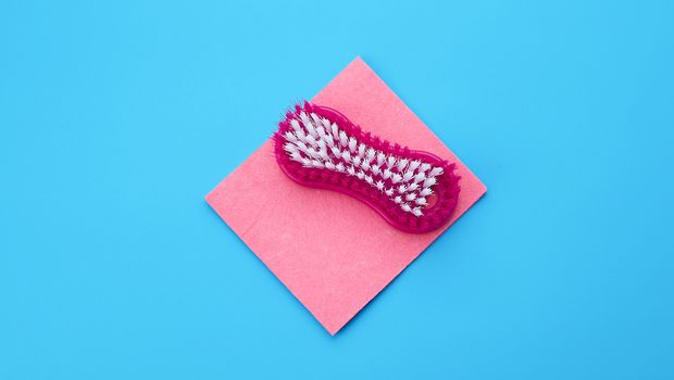 plastic pink brush and square dishwashing sponges on a blue background, top view, flat lay