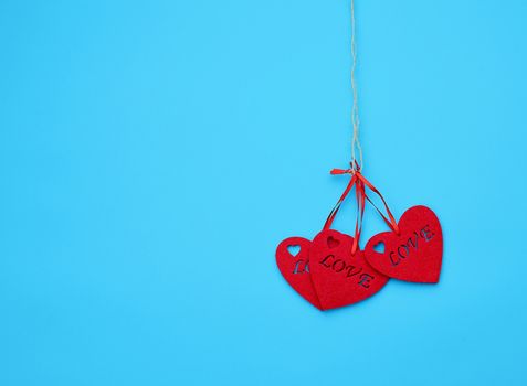 red felt hearts hanging on a brown rope, blue background. Holiday celebration concept. 