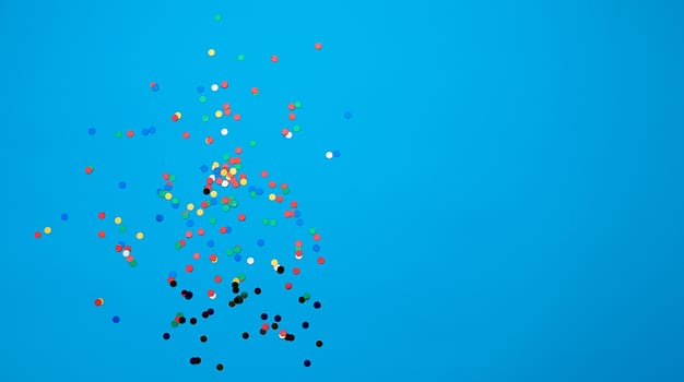 shiny multicolored round confetti scattered on a blue background, festive backdrop for birthday, valentines day. Festive decoration element. Flat design, copy space 