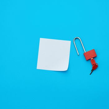 white paper and metal open padlock with keys on a blue background, copy space