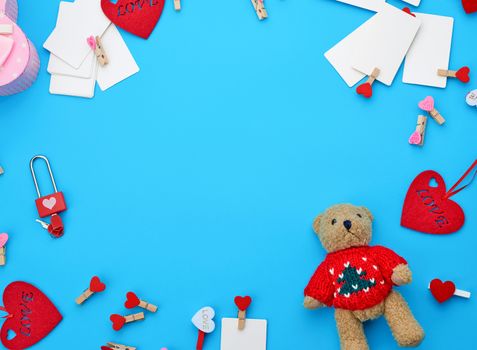 small teddy bear, white blank business cards with clothespins on a blue background, decor and objects for Valentine's Day, flat lay, copy space