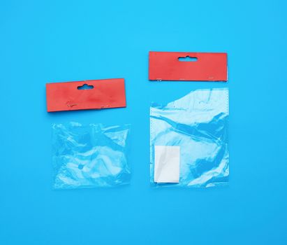 two transparent torn plastic bags with paper red top for packaging goods, blue background