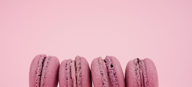 four round purple almond flour dessert macarons with cream on a pink background, delicious cake, close up, copy space
