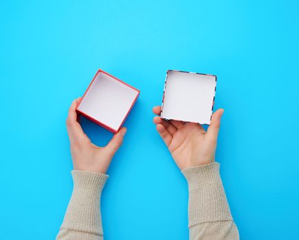 girl opens a brown square box on a blue background, top view, concept of giving gifts