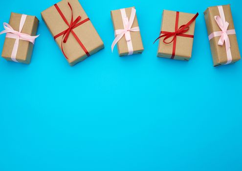 boxes wrapped in brown paper and tied with a red bow, gifts on a blue background, place for text