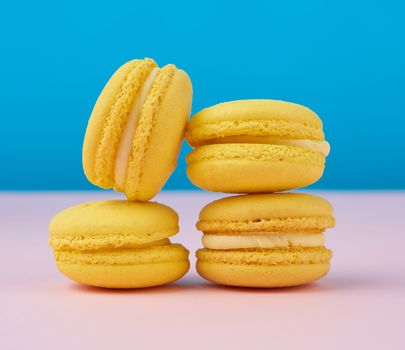 stack of baked round yellow lemon macarons on a blue-pink background,  delicious and delicious French dessert