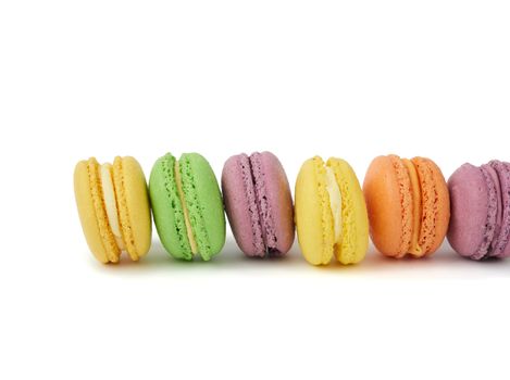 multicolored round baked macaroon cakes isolated on a white background, dessert stands in a row