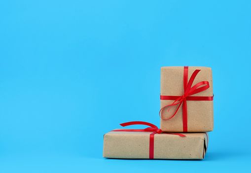 stack of boxes wrapped in brown paper and tied with a red bow, gifts on a blue background. Great design for any purposes. Holiday background. Valentine gift.