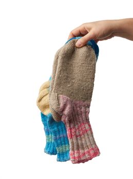 female hand holds a pair of knitted woolen socks, warm clothes, item is isolated on a white background 