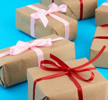 boxes wrapped in brown paper and tied with a silk ribbon, gifts on a blue background, top view. Festive concept
