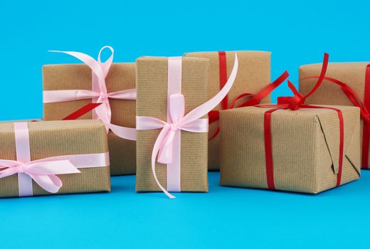 stack of boxes wrapped in brown paper and tied with a red bow, gifts on a blue background. Great design for any purposes. Holiday background. Valentine gift.