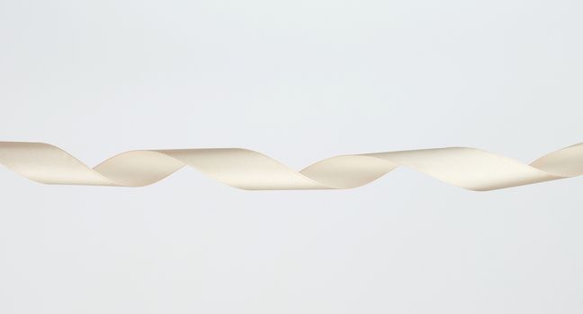 twisted beige silk decorative ribbon for packing gifts on a white background, close up