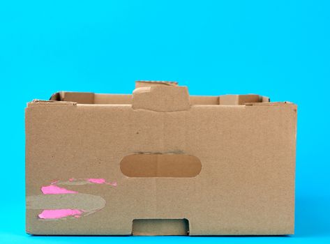 rectangular empty cardboard box of brown paper on a blue background, box without a lid for vegetables and fruits in with holes