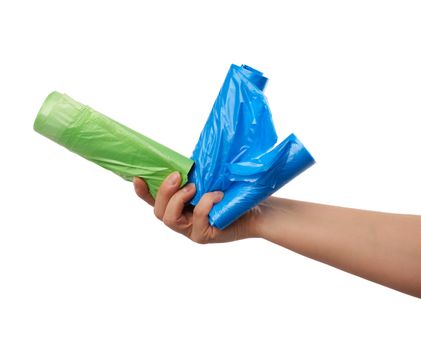 female hand holds a bundle of green and blue plastic bags for garbage, part of the body with the subject isolated on a white background