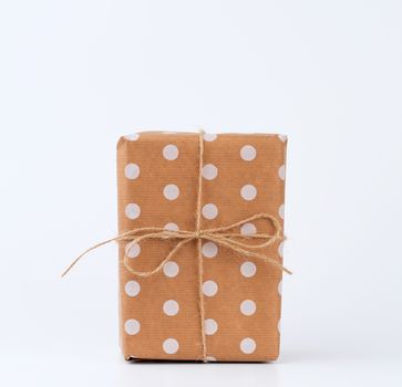 gift in box wrapped in brown kraft paper and tied with rope on a white background. Festive concept, copy space