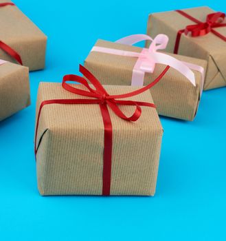 boxes wrapped in brown paper and tied with a silk ribbon, gifts on a blue background, top view. Festive concept