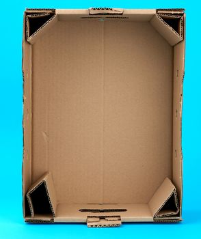 rectangular empty cardboard box of brown paper on a blue background, box without a lid for vegetables and fruits in with holes