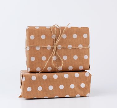 stack of gifts in boxes wrapped in brown kraft paper and tied with rope on a white background. Festive concept, copy space
