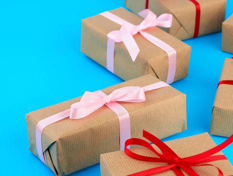 boxes wrapped in brown paper and tied with a silk ribbon, gifts on a blue background, top view. Festive concept