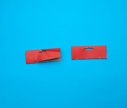 two red cardboard pieces of paper on a blue background, close up