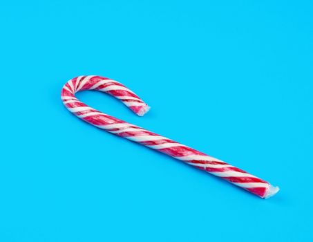red-white candy stick in transparent cellophane on a blue background