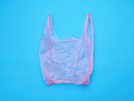open empty plastic pink bag for products on a blue background, concept of rejection of plastic bags to save the environment
