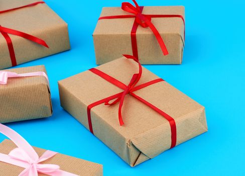 boxes wrapped in brown paper and tied with a silk ribbon, gifts on a blue background, top view. Festive concept