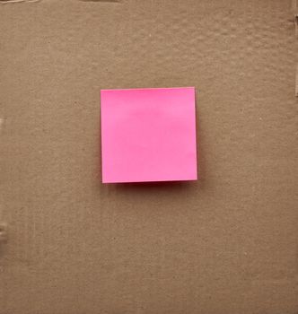 blank pink square paper glued on a brown cardboard surface. Design template.