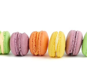 multicolored round baked macaroon cakes isolated on a white background, dessert stands in a row, close up