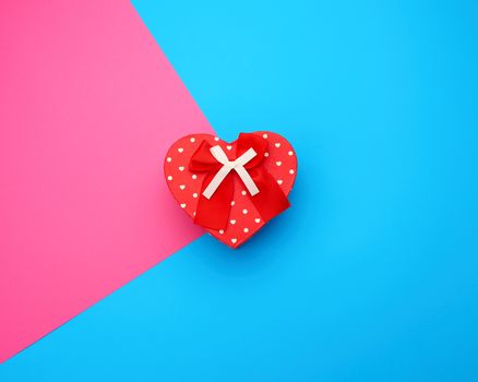 red gift box in the form of a heart with a bow on a blue background, festive backdrop