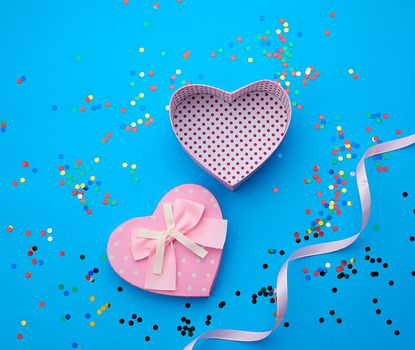open pink heart-shaped cardboard box on a pink background with multi-colored shiny confetti, festive backdrop for birthday, Valentine's day