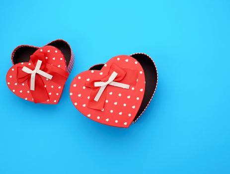 open empty red cardboard box in the form of a heart on a light blue background, top view, element for a designer